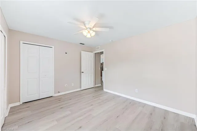an empty room with wooden floor and fan