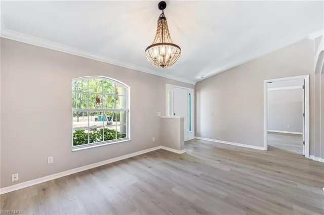 an empty room with wooden floor cabinet and windows