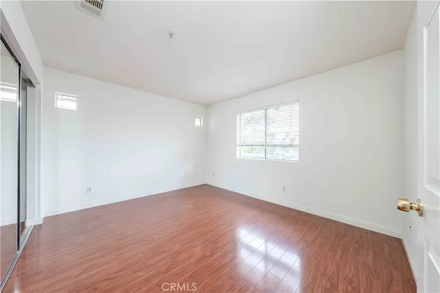 a view of an empty room with wooden floor and closet