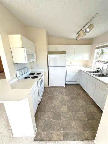a large white kitchen with a stove a sink and a refrigerator
