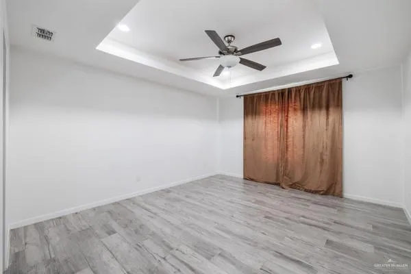 an empty room with wooden floor fan and windows
