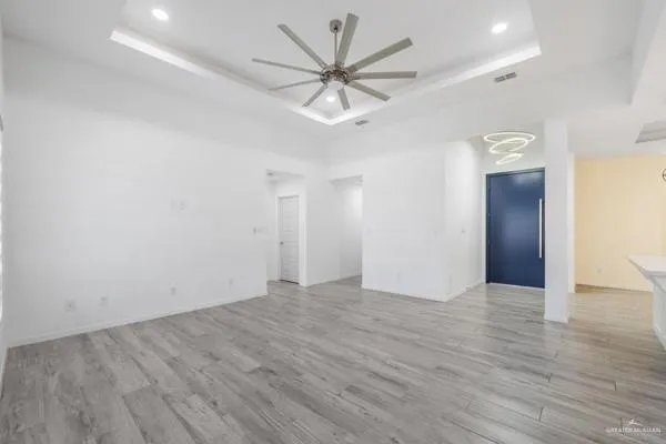an empty room with wooden floor and a ceiling fan