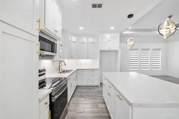 a large kitchen with stainless steel appliances granite countertop a lot of counter space and a sink