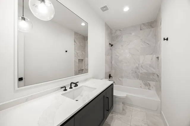 a bathroom with a bathtub sink vanity granite and toilet