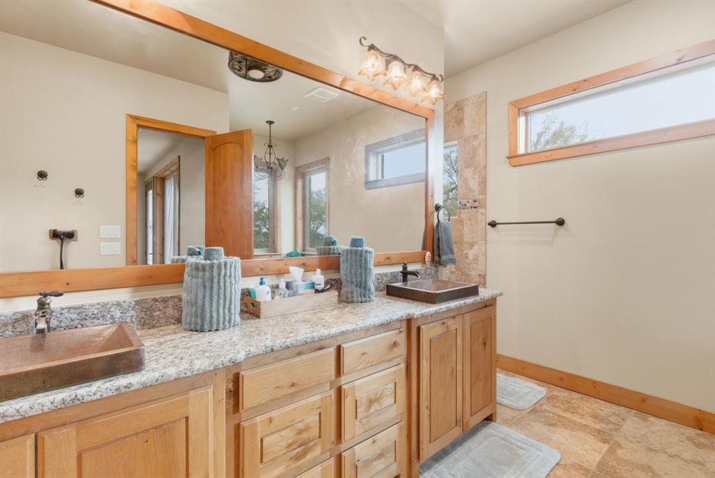 735 Gresham Lane Jacksboro, TX 76458 - Photo 14 of 40 a bathroom with a granite countertop sink a mirror and a shower