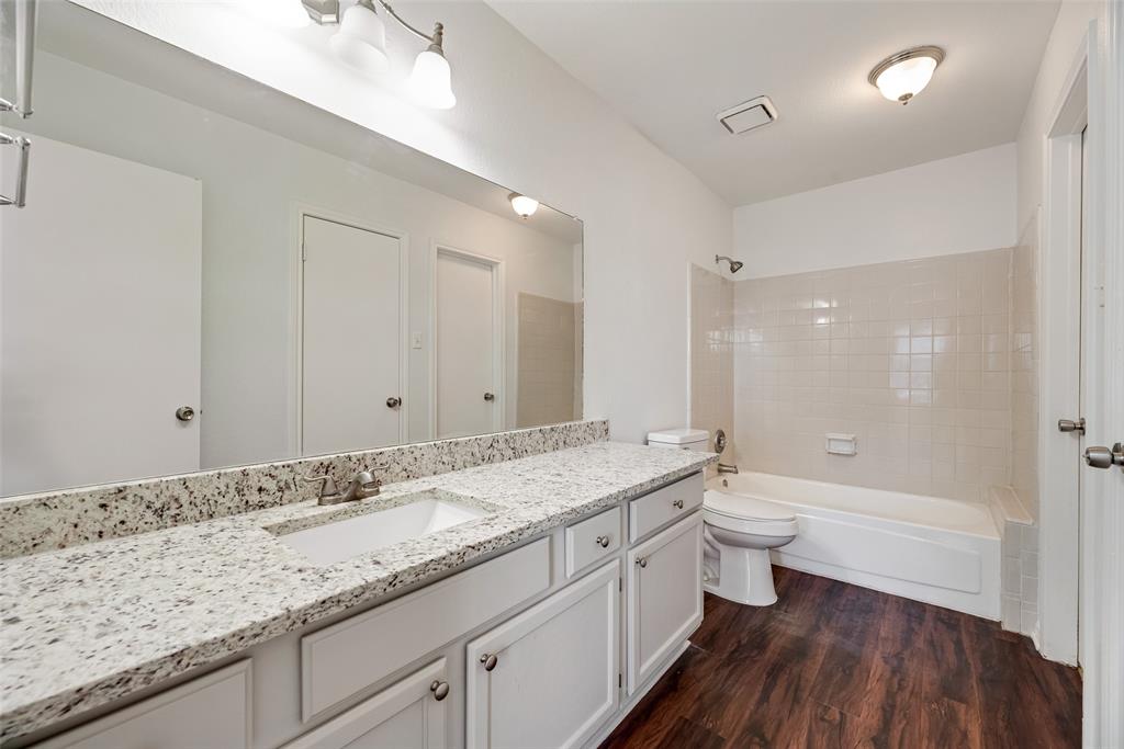 449 Harris Street, Unit 101L Coppell, TX 75019 - Photo 14 of 22 a bathroom with a granite countertop sink a toilet and shower
