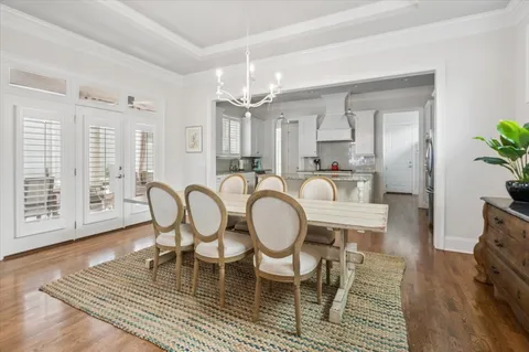 a dining room with furniture a rug a potted plant and wooden floor