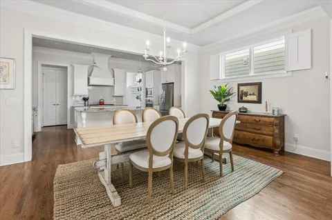 a dining room with furniture a chandelier and wooden floor