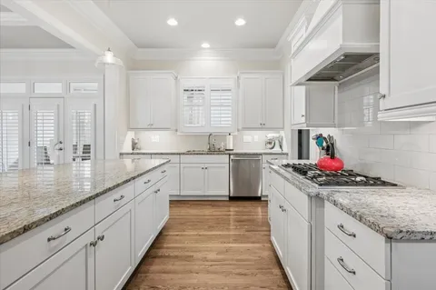 a kitchen that has a lot of cabinets in it and wooden floors