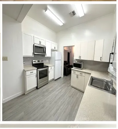 a large kitchen with cabinets wooden floor and stainless steel appliances