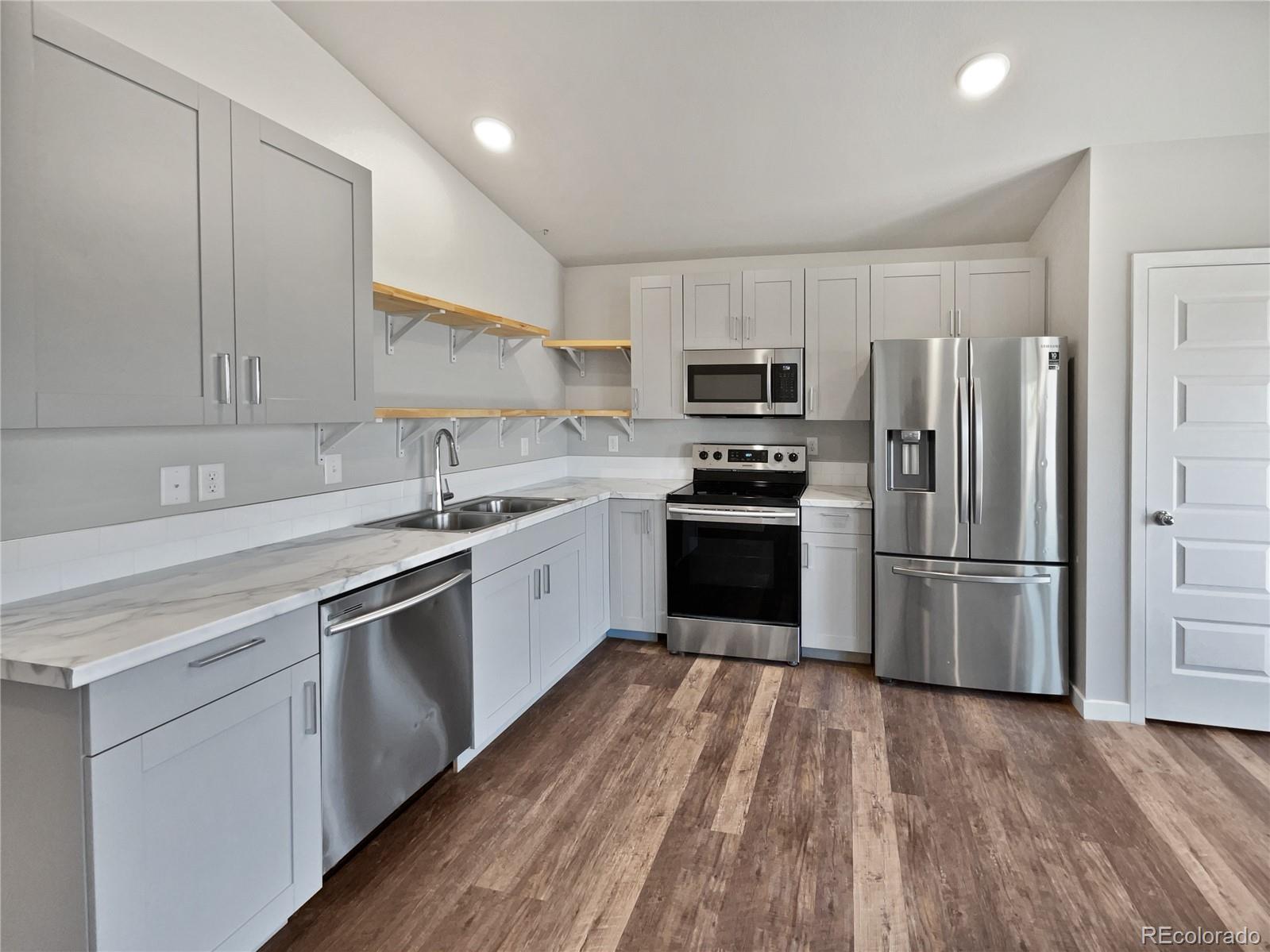 322 Bozeman Trail Ault, CO 80610 - Photo 6 of 19 a kitchen with a sink a refrigerator and white cabinets