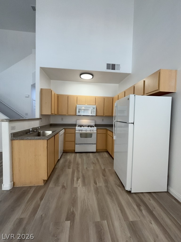 4915 East Russell Road, Unit 144 Las Vegas, NV 89120 - Photo 5 of 14 Kitchen with white appliances, dark countertops, light wood finish cabinets, light wood finished floors, and a high ceiling