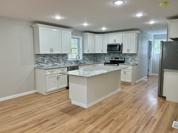 1 Heritage Lane Monson, MA 01057 - Photo 6 of 23 a kitchen with stainless steel appliances granite countertop a stove top oven a sink dishwasher a refrigerator and white cabinets with wooden floor