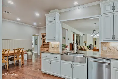 a kitchen with white cabinets and chairs