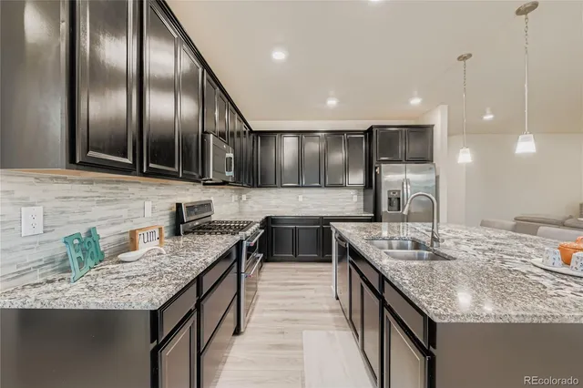 a kitchen with granite countertop stainless steel appliances a sink stove and cabinets