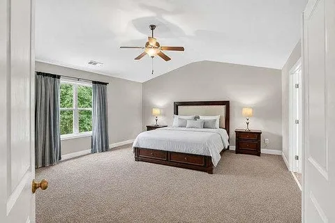 a bedroom with a large bed and a chandelier fan
