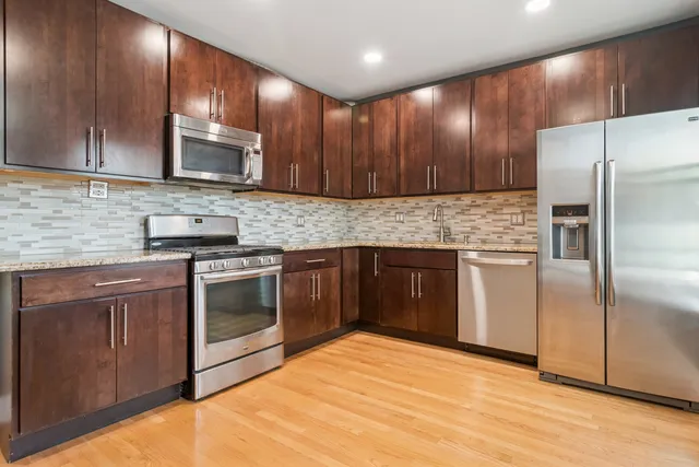 a kitchen with stainless steel appliances granite countertop wooden cabinets a stove top oven a sink and dishwasher