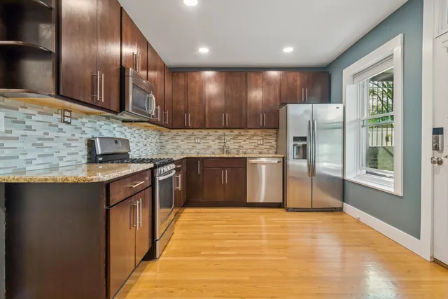 a kitchen with stainless steel appliances granite countertop a refrigerator a sink a stove and a microwave