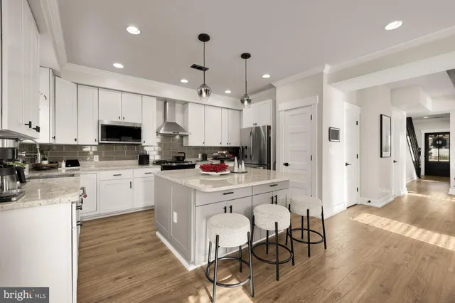 a kitchen with stainless steel appliances granite countertop a sink a stove a refrigerator cabinets and a dining table with wooden floor