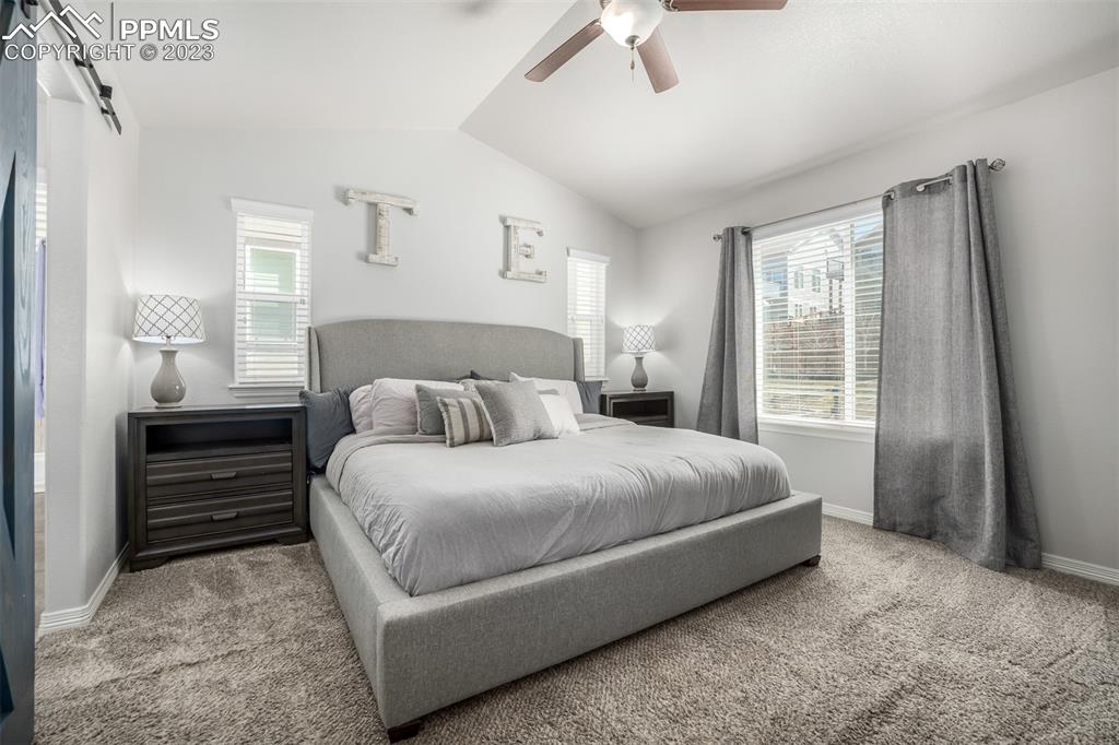 17835 Mining Way Monument, CO 80132 - Photo 20 of 49 a large bed sitting in a bedroom next to a window and a chandelier