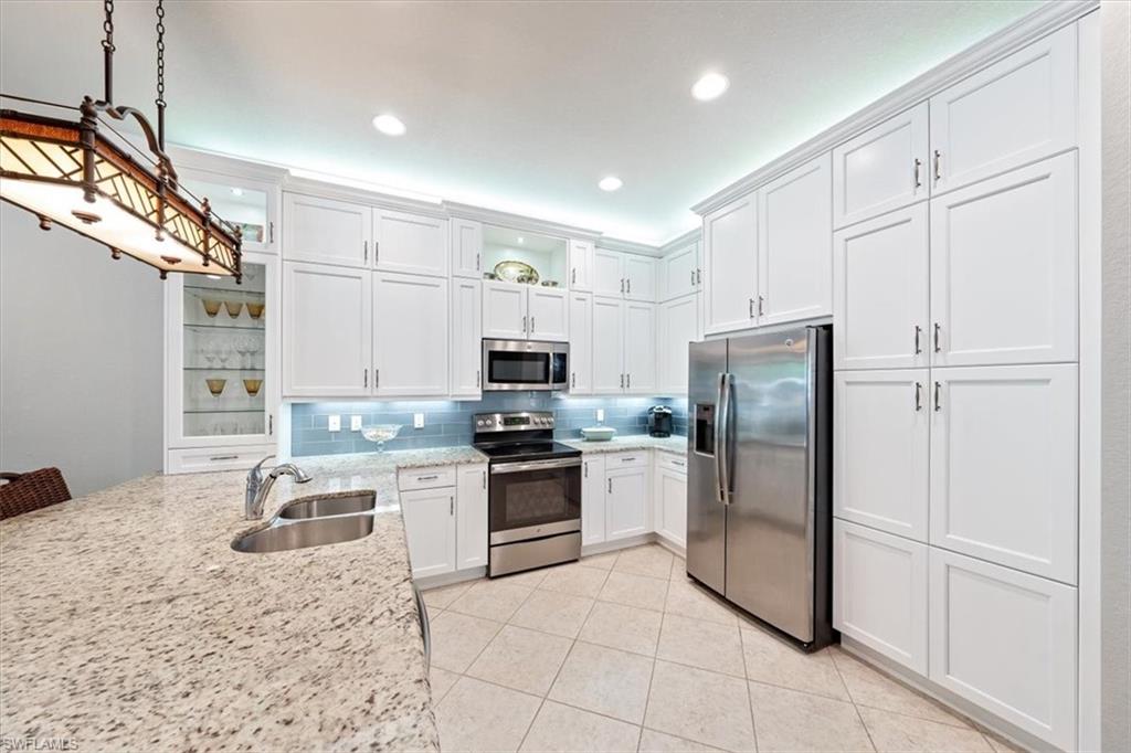 13576 Mandarin Circle Naples, FL 34109 - Photo 11 of 24 a kitchen with stainless steel appliances granite countertop a refrigerator sink and stove