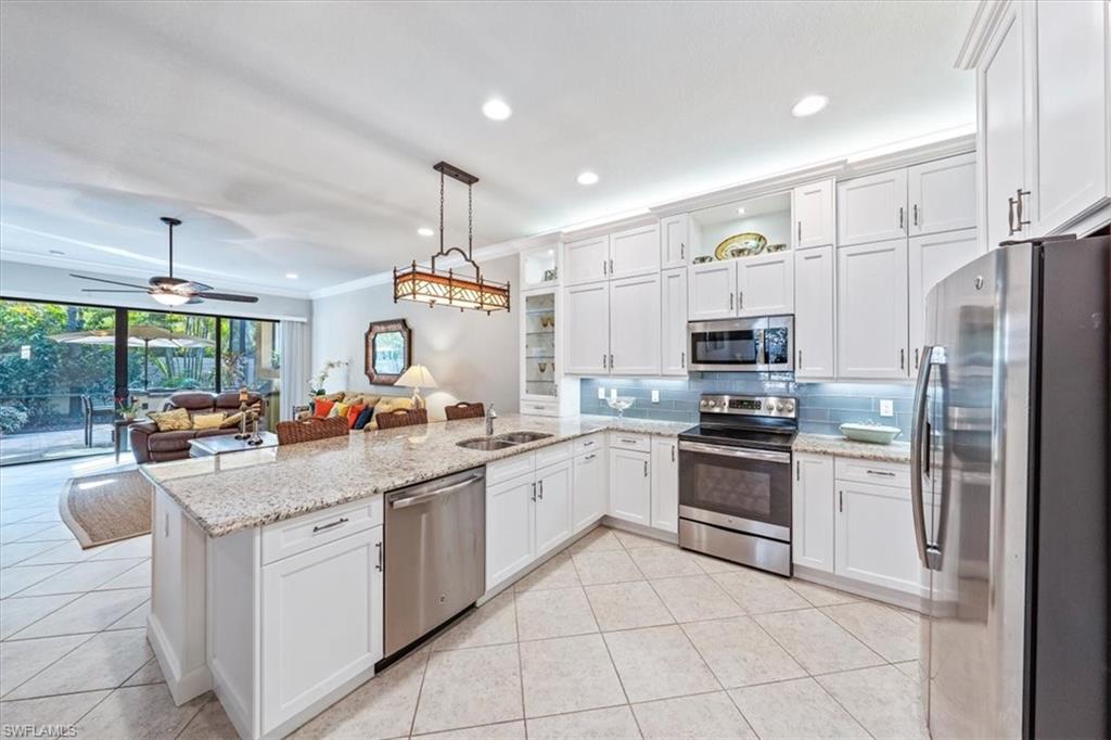 13576 Mandarin Circle Naples, FL 34109 - Photo 10 of 24 a kitchen with white cabinets and stainless steel appliances