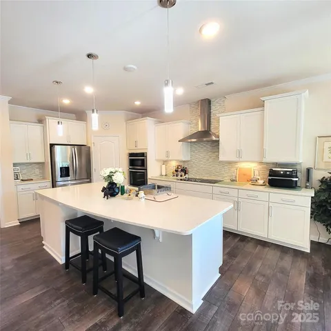 a kitchen with a sink a stove a refrigerator and white cabinets with wooden floor