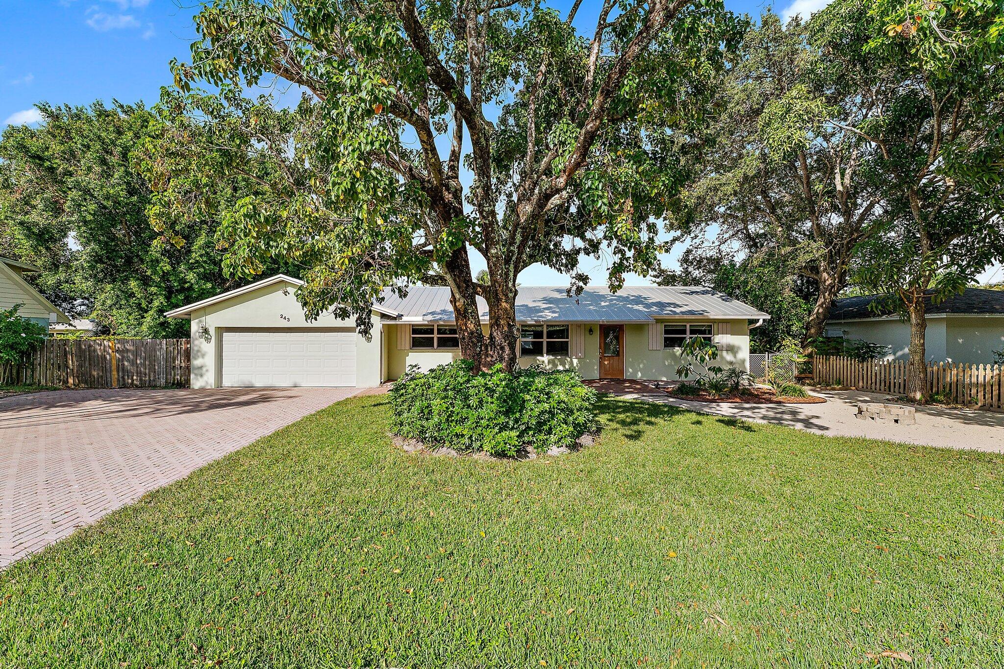 243 West Riverside Drive Jupiter, FL 33469 - Photo 1 of 67 a front view of a house with yard and sitting area