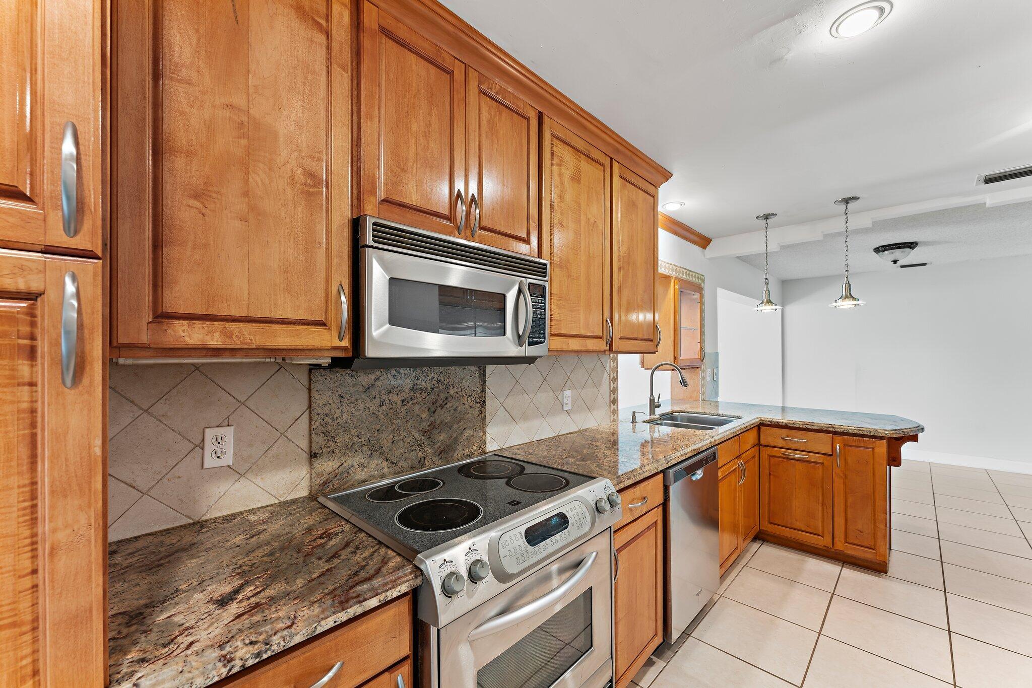 243 West Riverside Drive Jupiter, FL 33469 - Photo 23 of 67 a kitchen with stainless steel appliances granite countertop a sink stove and microwave