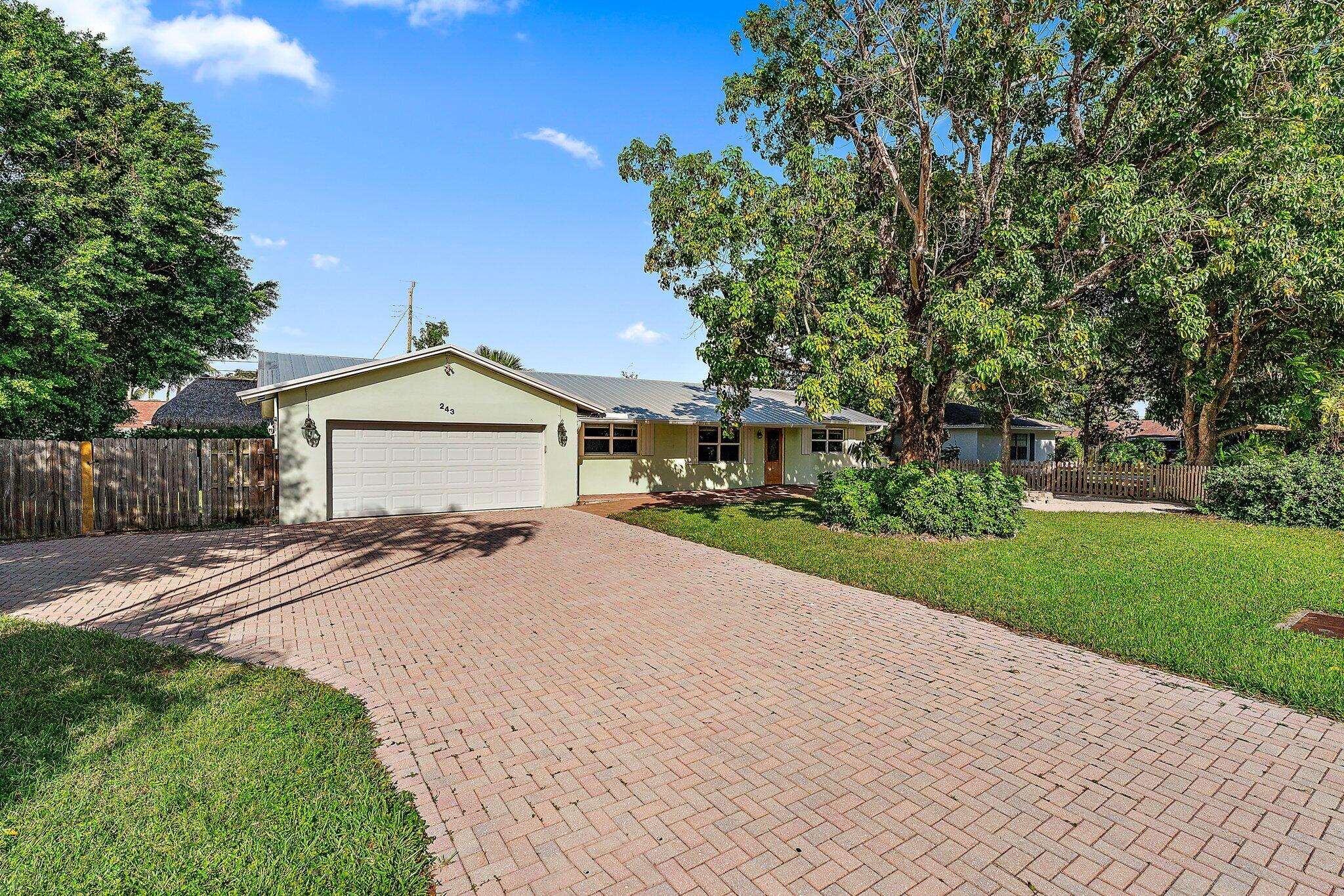 243 West Riverside Drive Jupiter, FL 33469 - Photo 7 of 67 a front view of a house with a yard and garage