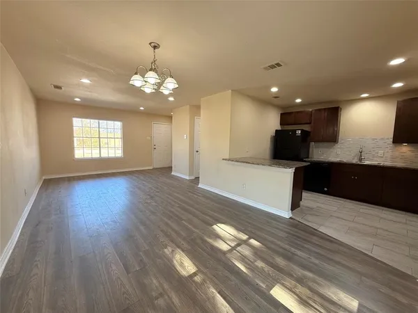 a view of a kitchen with granite countertop a stove top oven a sink and wooden floors