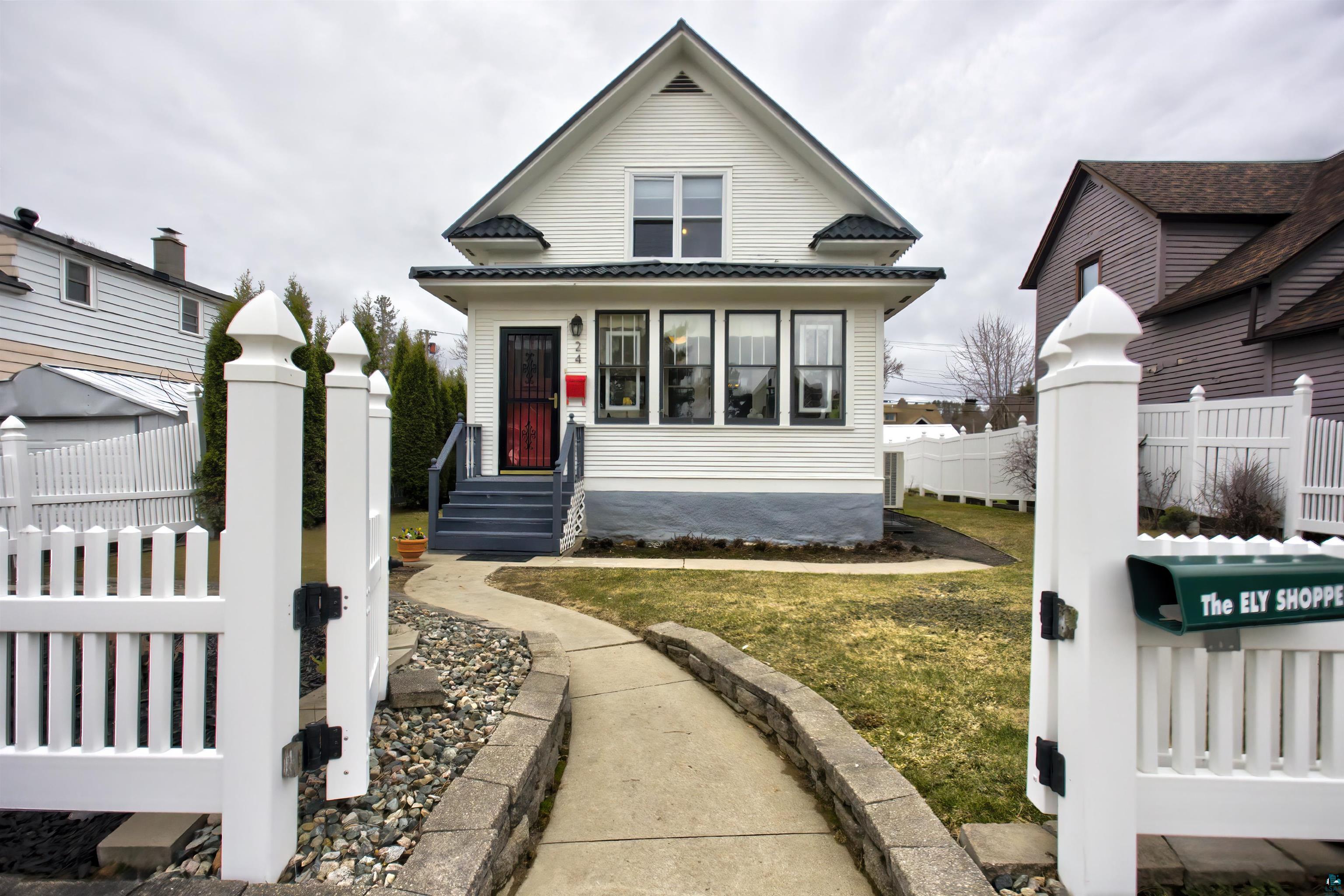 24 East Conan Street Ely, MN 55731 - Photo 1 of 27 Charming home featuring white siding, a contrasting dark roof, and a red entry door