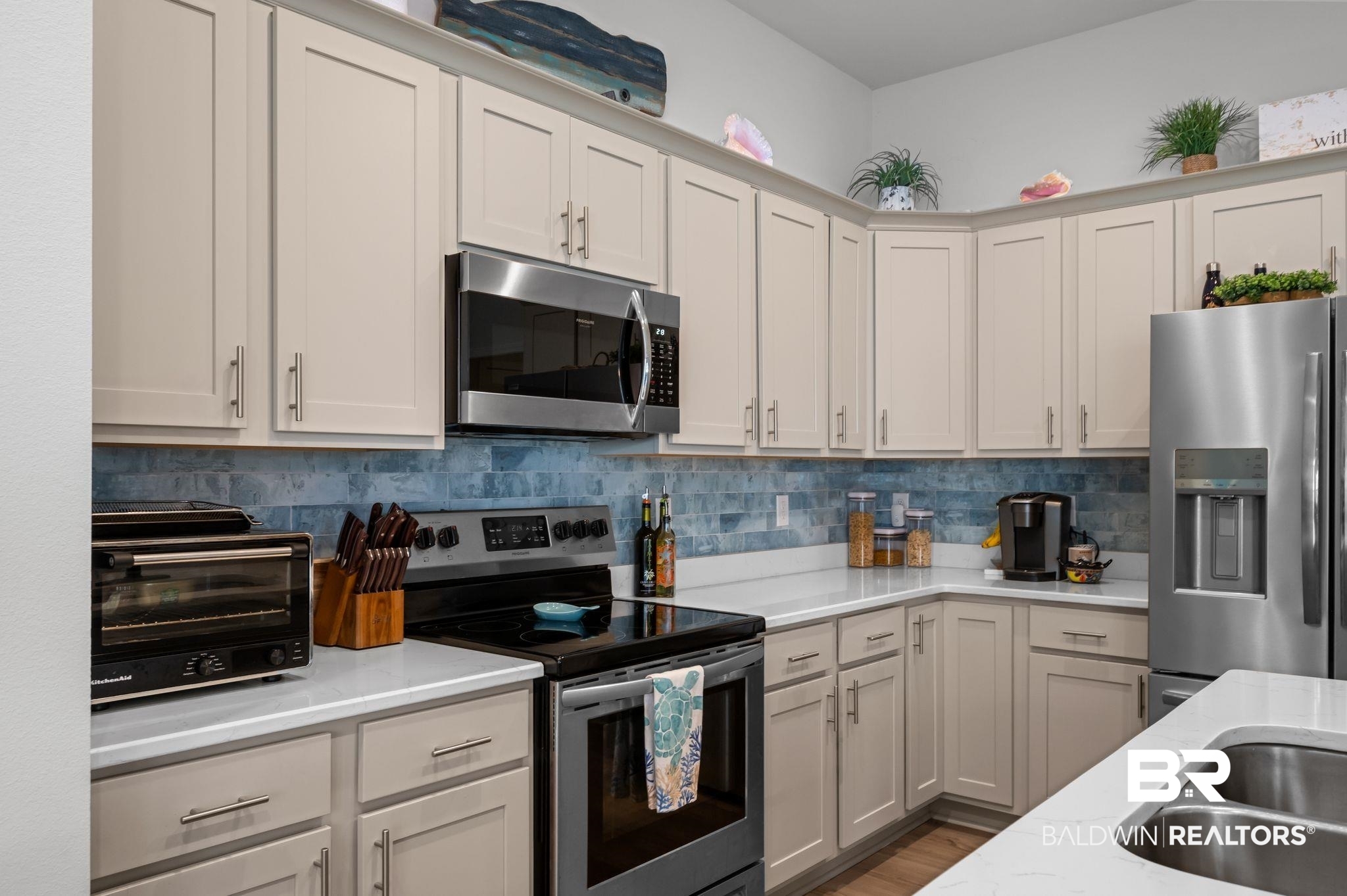 1165 Stella Road Foley, AL 36535 - Photo 13 of 42 Kitchen with appliances with stainless steel finishes, light stone countertops, decorative backsplash, and wood finished floors