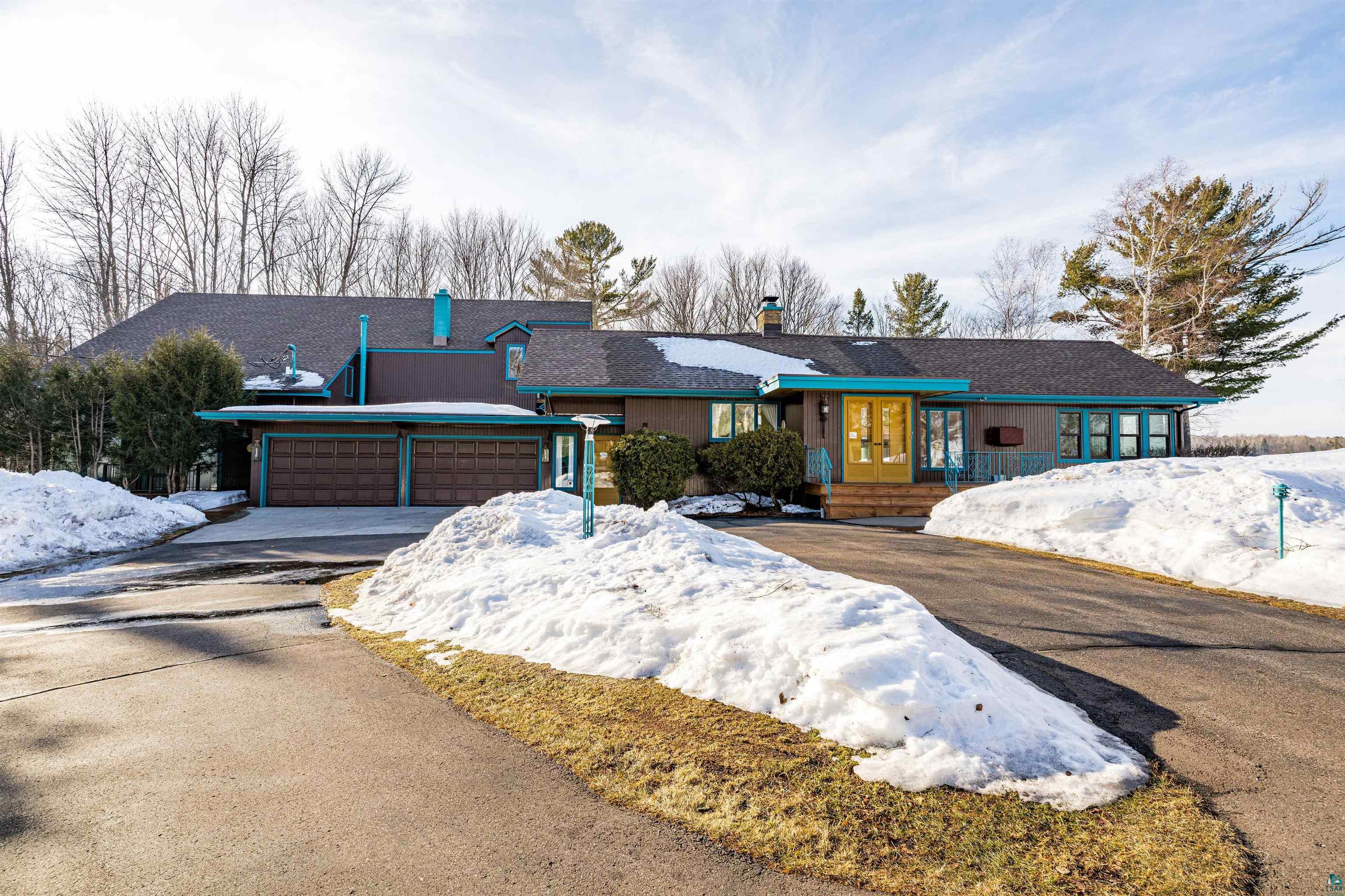 Ranch-style home with a chimney, an attached garage, asphalt driveway, and a porch