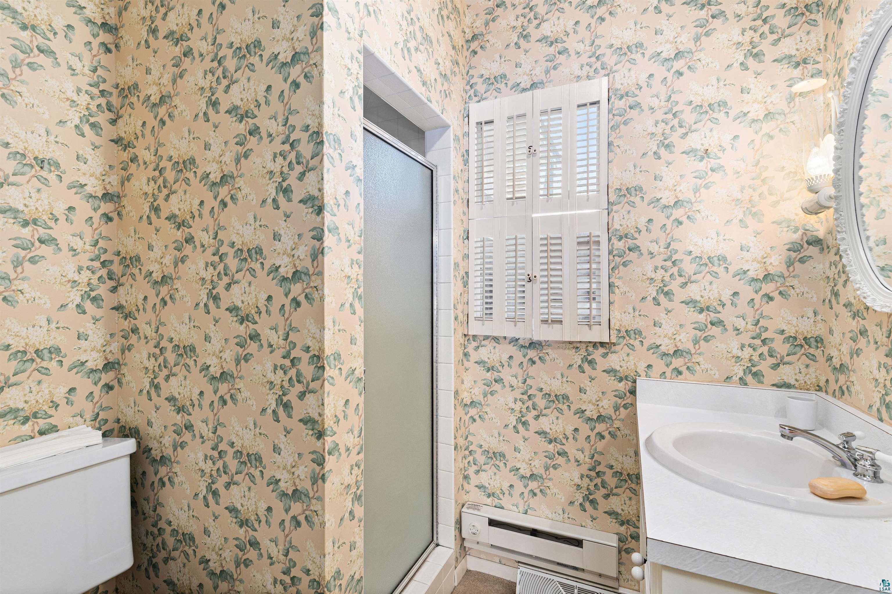 5781 South Pike Lake Road Duluth, MN 55811 - Photo 12 of 42 Bathroom featuring wallpapered walls, baseboard heating, vanity, and a stall shower