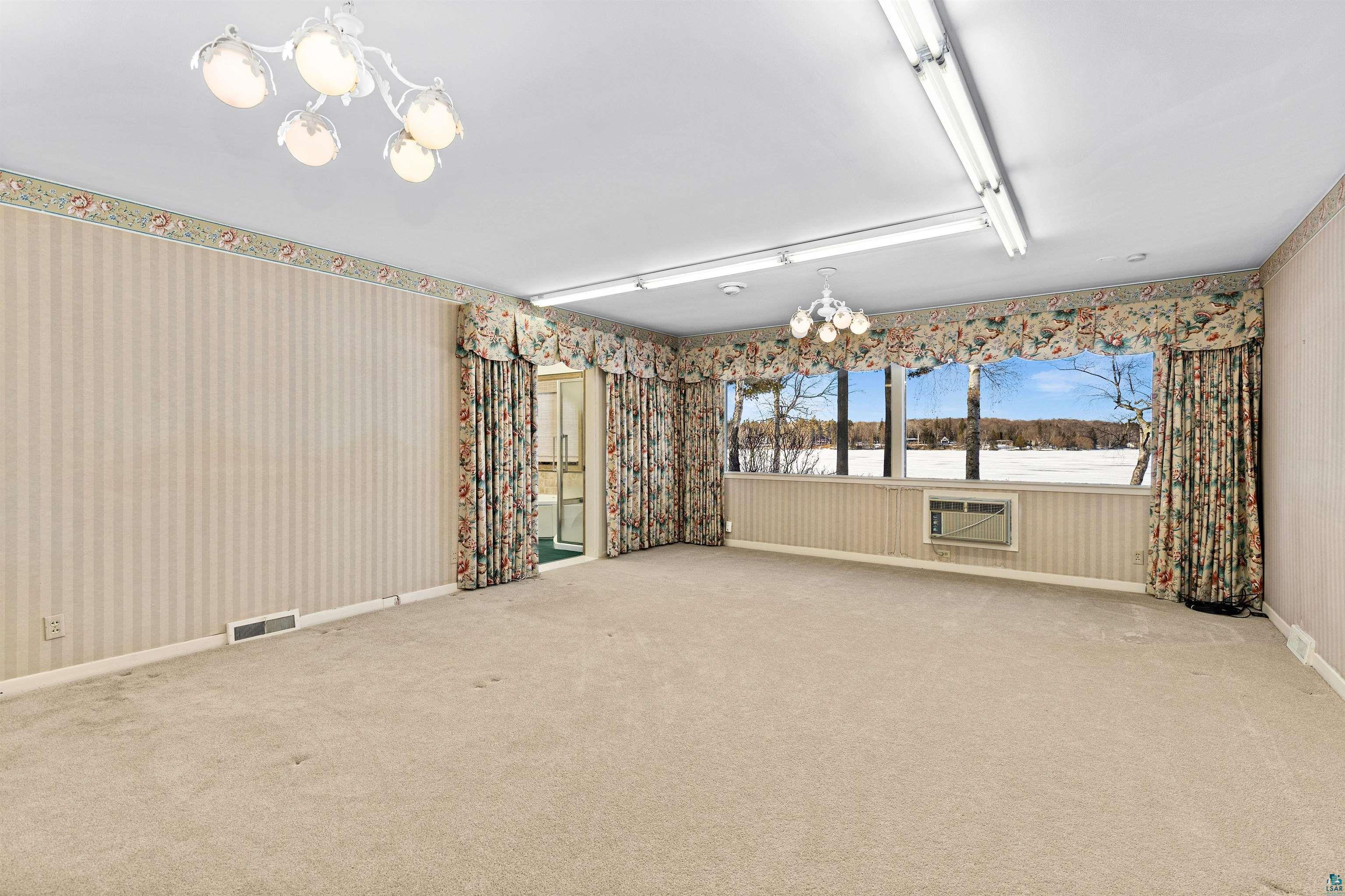 5781 South Pike Lake Road Duluth, MN 55811 - Photo 18 of 42 Unfurnished room with suspended lighting, wallpapered walls, and carpet floors