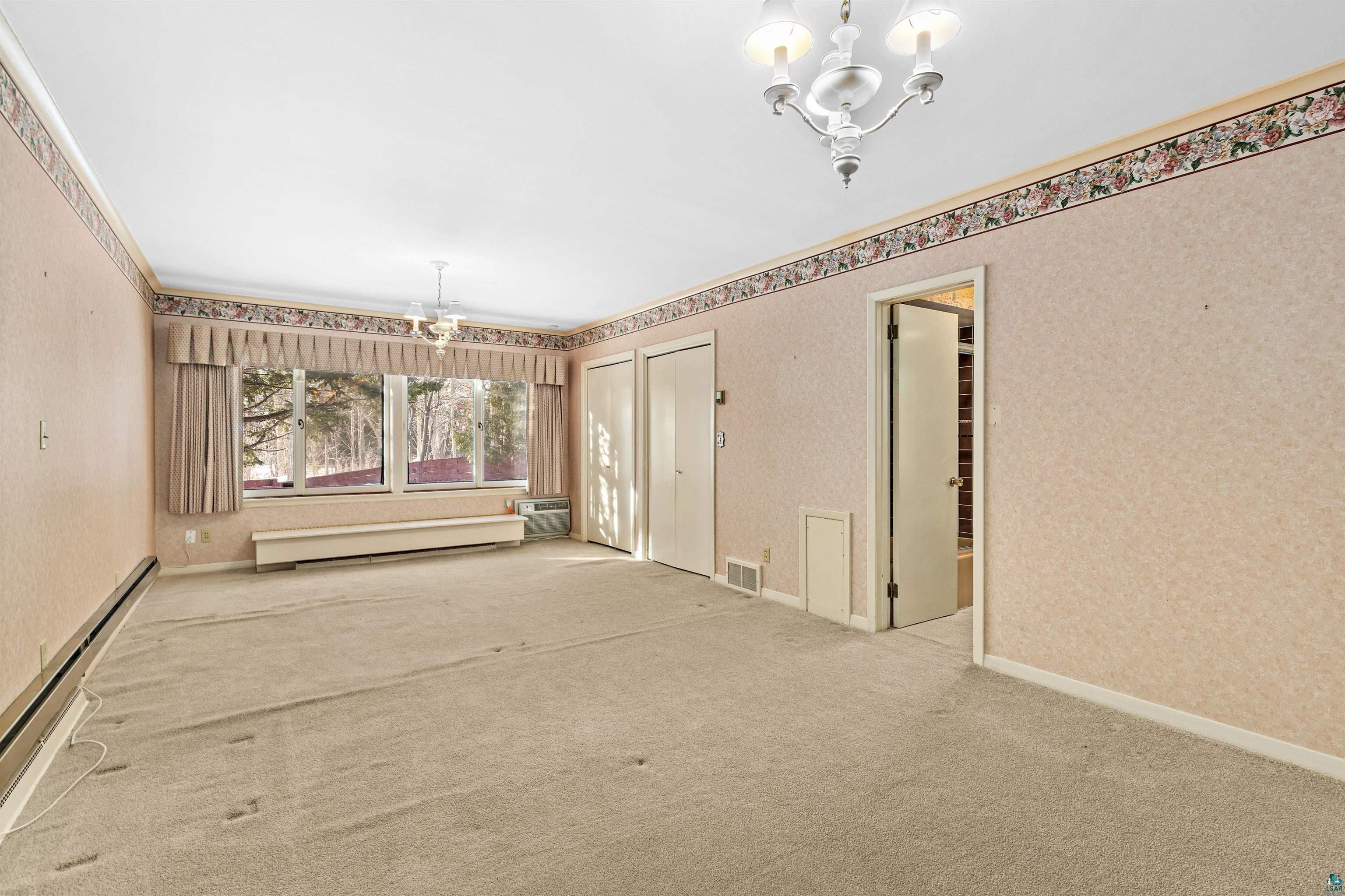 5781 South Pike Lake Road Duluth, MN 55811 - Photo 19 of 42 Unfurnished dining area featuring suspended lighting, a baseboard heating unit, carpet flooring, wallpapered walls, and crown molding