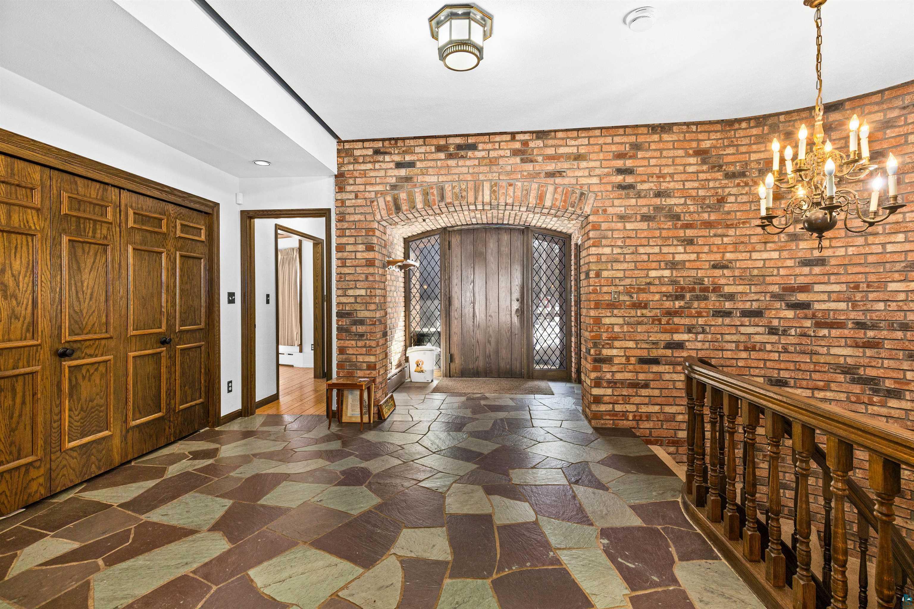 5781 South Pike Lake Road Duluth, MN 55811 - Photo 30 of 42 Entrance foyer featuring hanging lights, brick wall, stone tile floors, and arched walkways