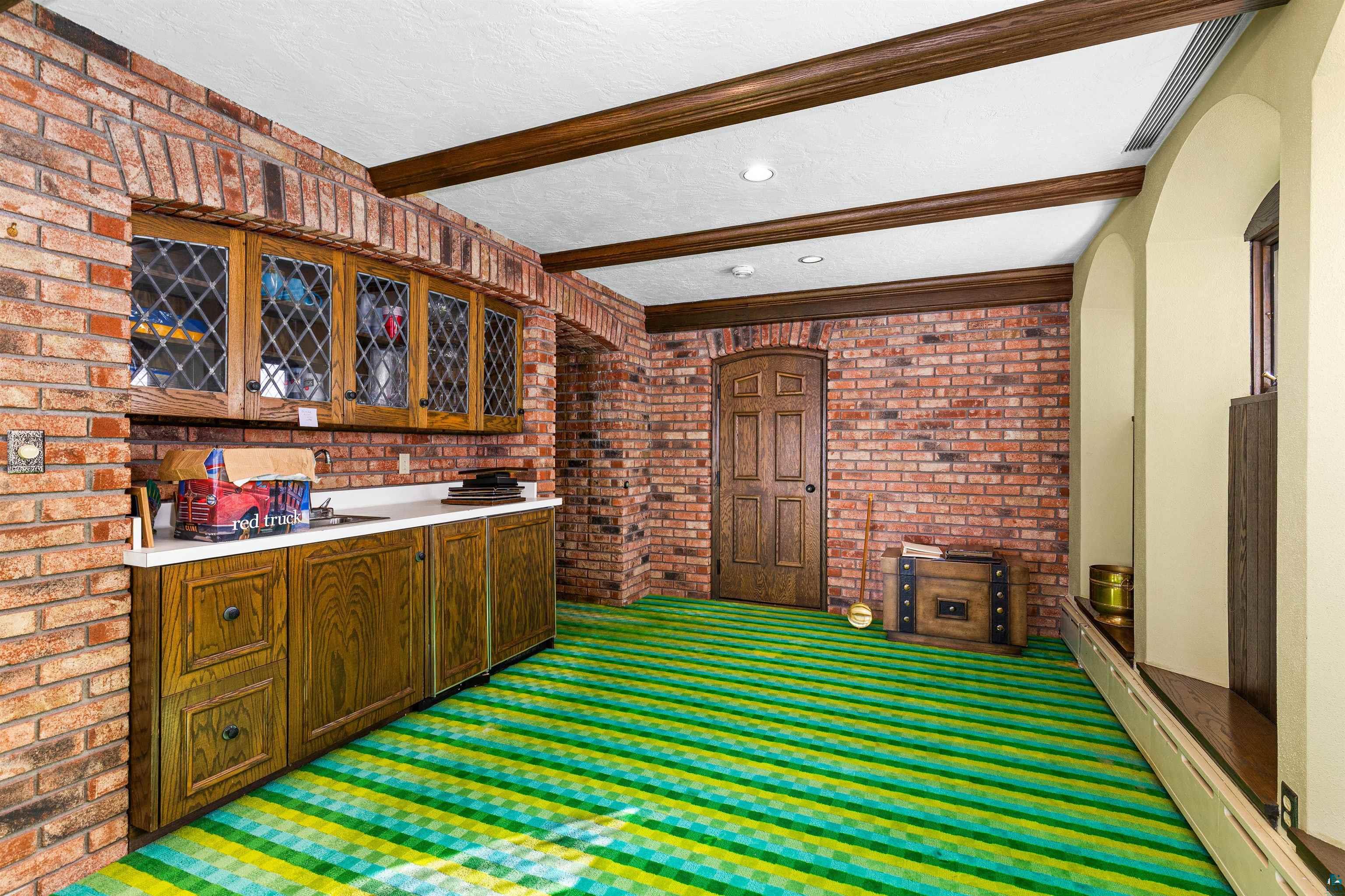 5781 South Pike Lake Road Duluth, MN 55811 - Photo 38 of 42 Bar with brick wall, dark colored carpet, beamed ceiling, light countertops, and arched walkways