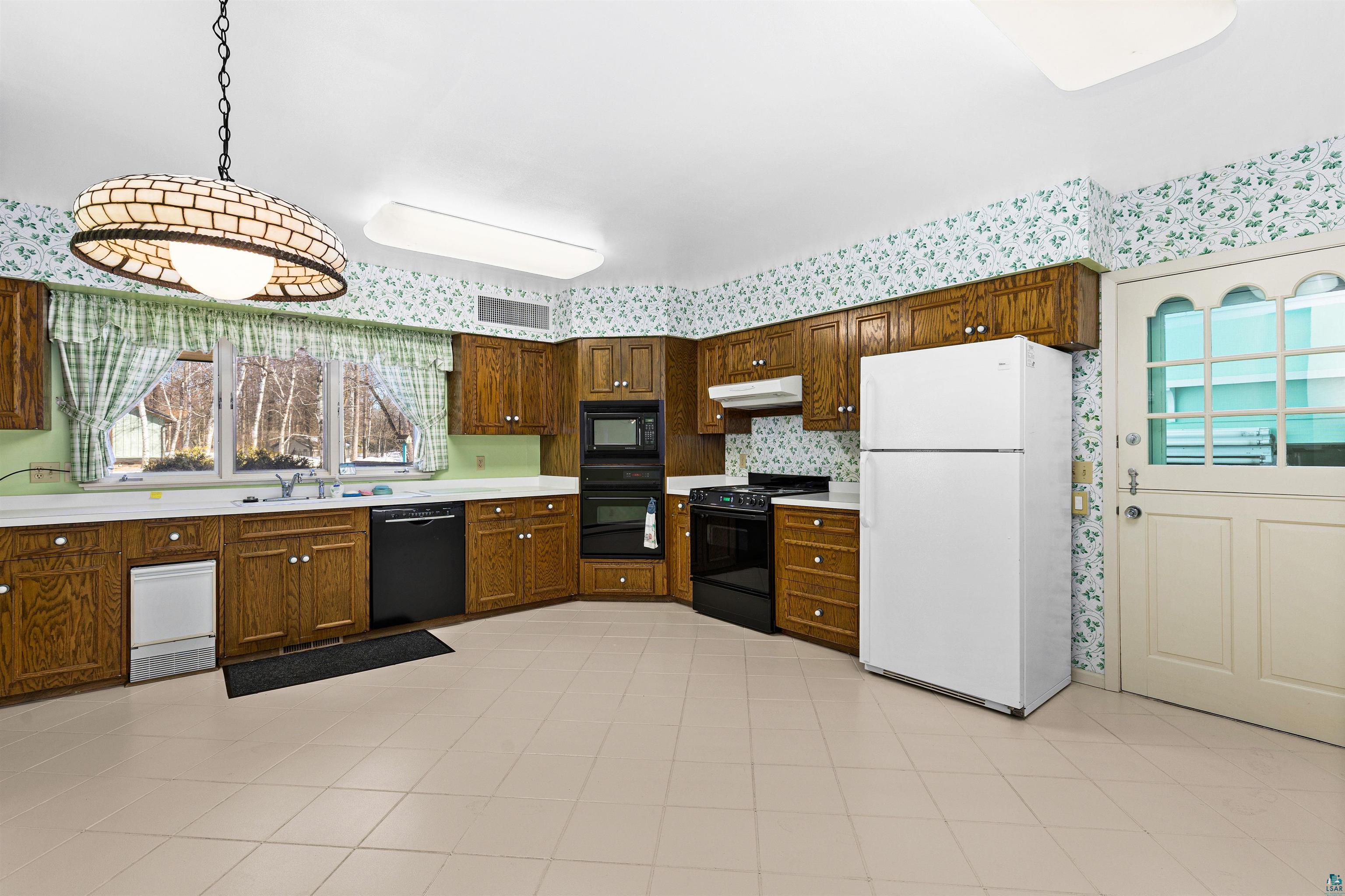 5781 South Pike Lake Road Duluth, MN 55811 - Photo 7 of 42 Kitchen featuring light countertops, black appliances, decorative light fixtures, wood finish cabinets, and light tile patterned flooring