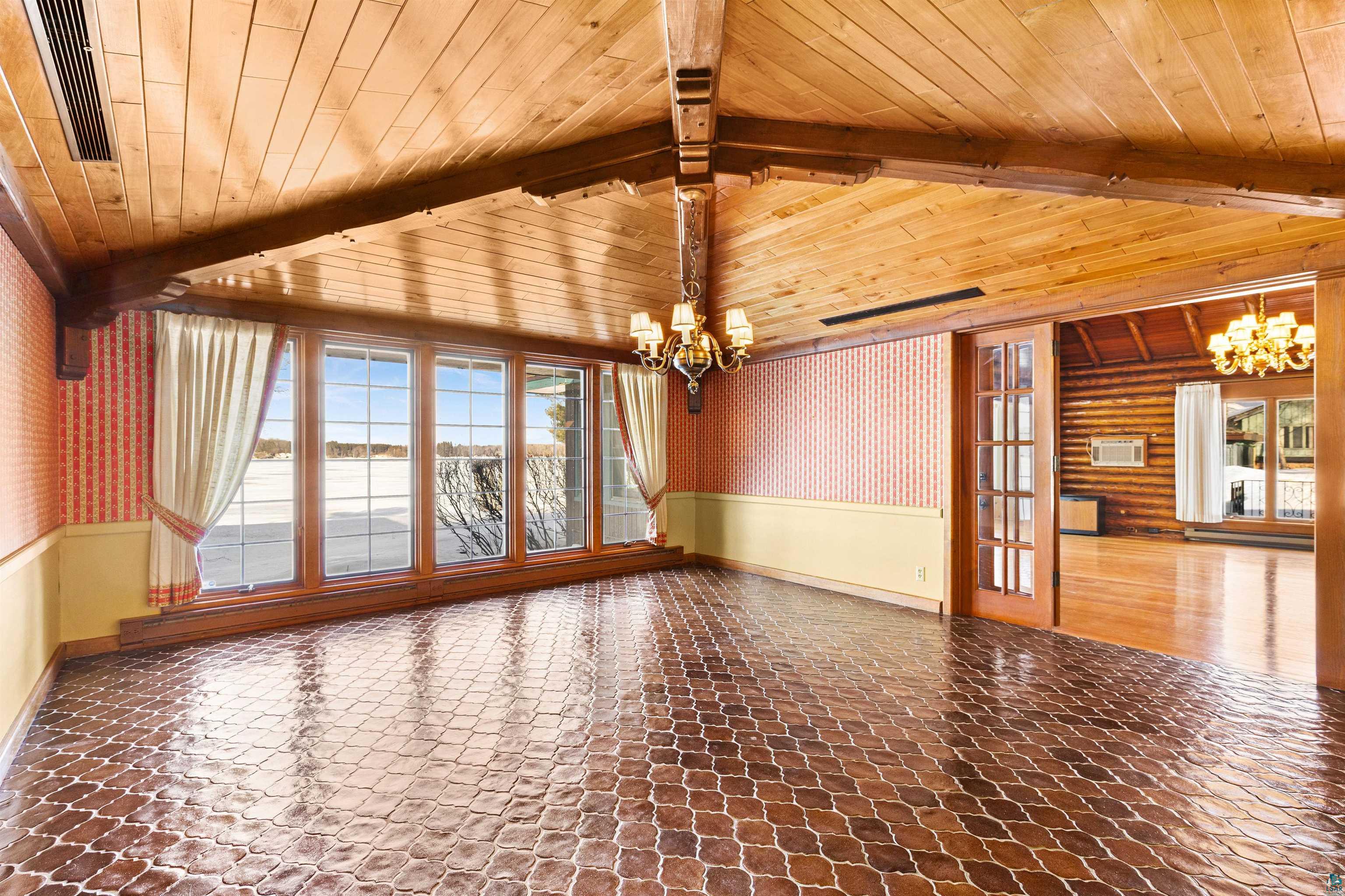 5781 South Pike Lake Road Duluth, MN 55811 - Photo 10 of 42 Spare room with wallpapered walls, suspended lighting, a wainscoted wall, and vaulted ceiling with beams