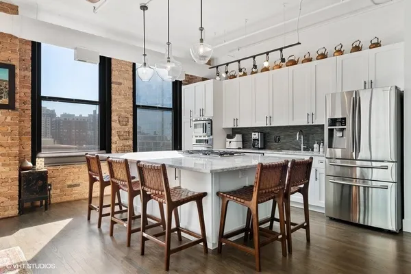 a kitchen with stainless steel appliances granite countertop a table chairs and a refrigerator