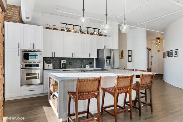 a kitchen with stainless steel appliances kitchen island granite countertop a table chairs sink and cabinets