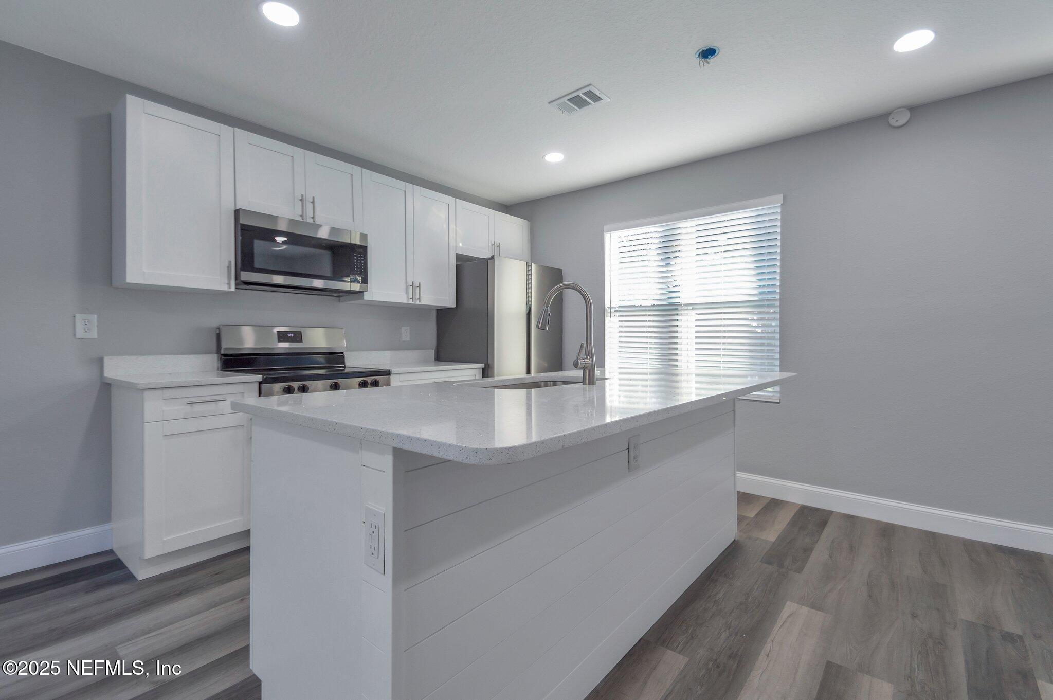 1759 Planters Road Jacksonville, FL 32207 - Photo 4 of 16 a kitchen with stainless steel appliances a sink a stove a microwave and cabinets