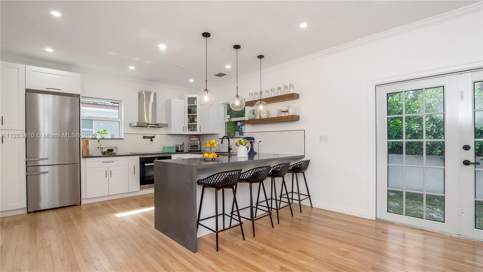 635 Bird Road Coral Gables, FL 33146 - Photo 13 of 35 a kitchen with stainless steel appliances a dining table chairs stove refrigerator and cabinets