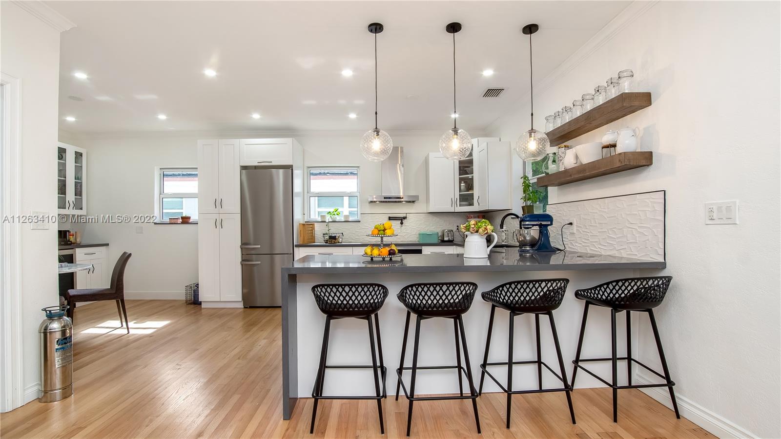 635 Bird Road Coral Gables, FL 33146 - Photo 14 of 35 a kitchen with stainless steel appliances kitchen island granite countertop a table chairs sink and wooden floor