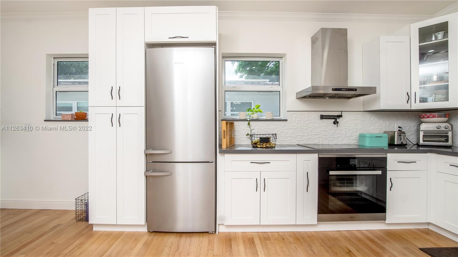 635 Bird Road Coral Gables, FL 33146 - Photo 17 of 35 a kitchen with stainless steel appliances granite countertop a refrigerator and a stove top oven