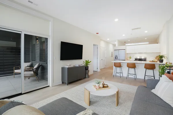 a living room with furniture kitchen view and a flat screen tv