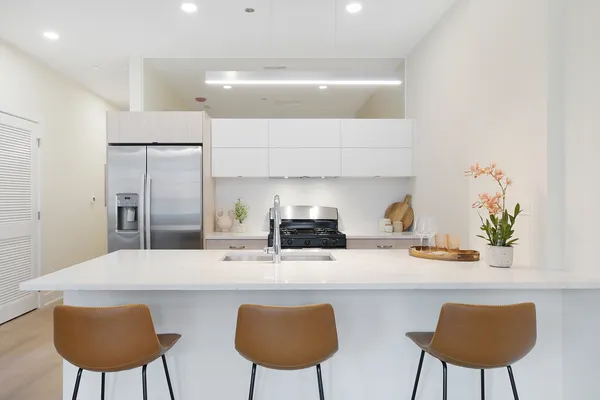 a kitchen with stainless steel appliances a dining table chairs and a refrigerator
