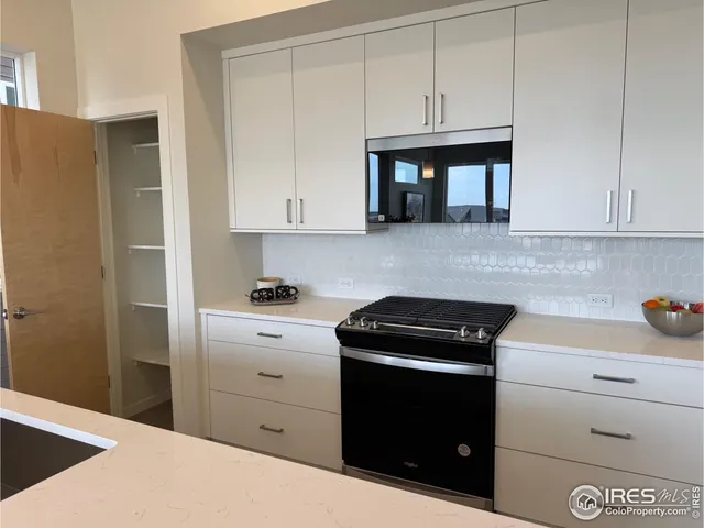 a kitchen with granite countertop white cabinets and black appliances